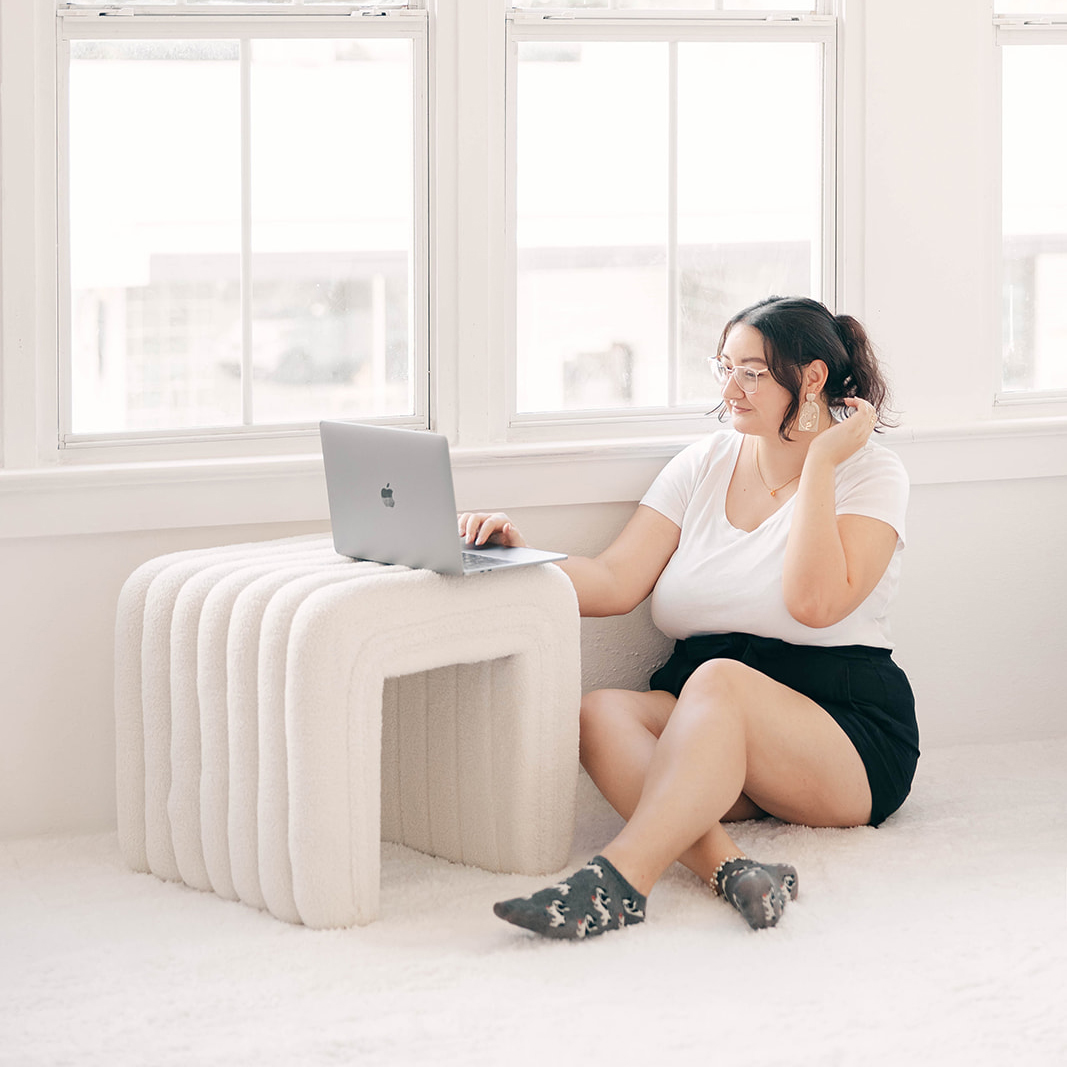 graphic designer sitting on floor working on laptop