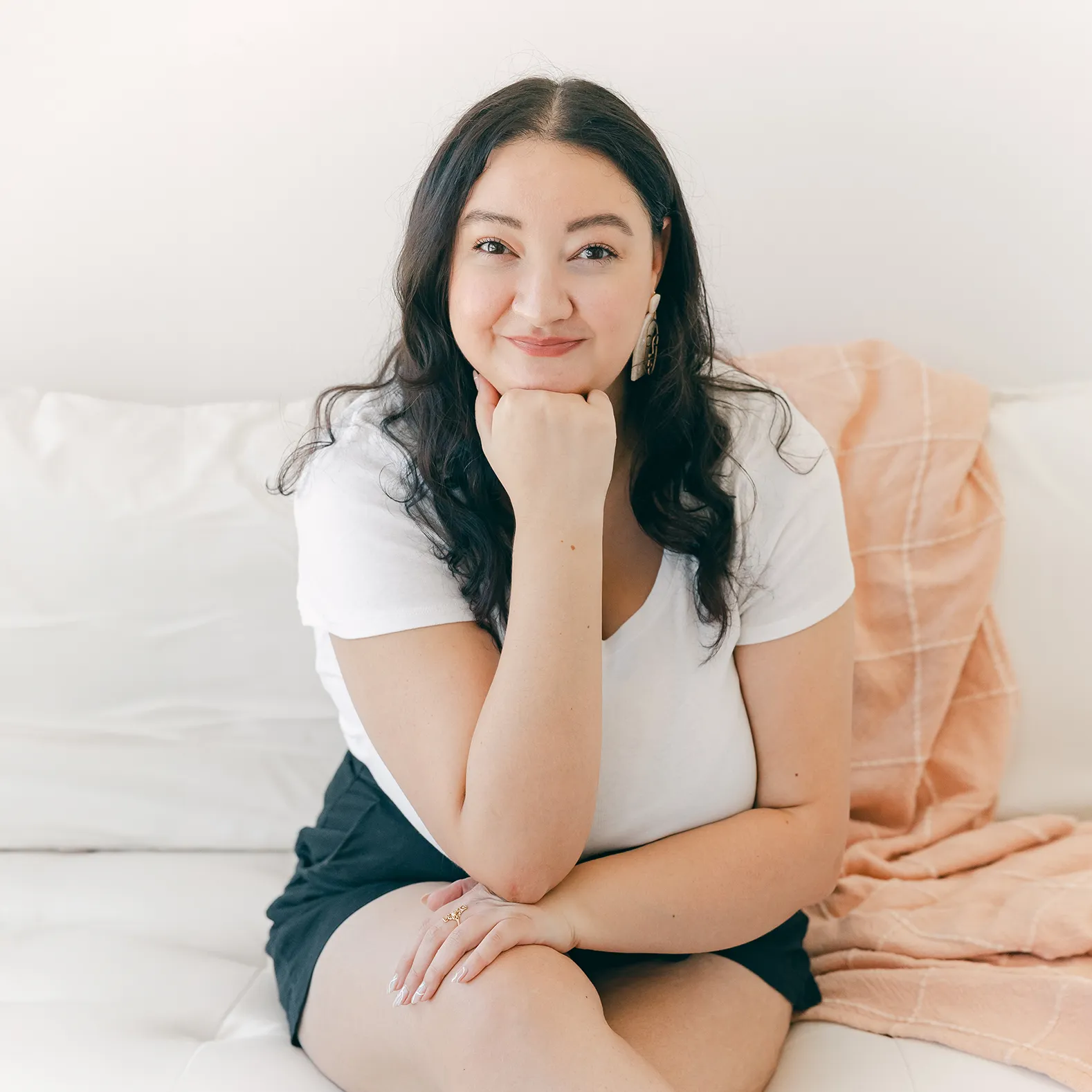 Kimberly sitting on a couch and smiling with her head propped on her hand